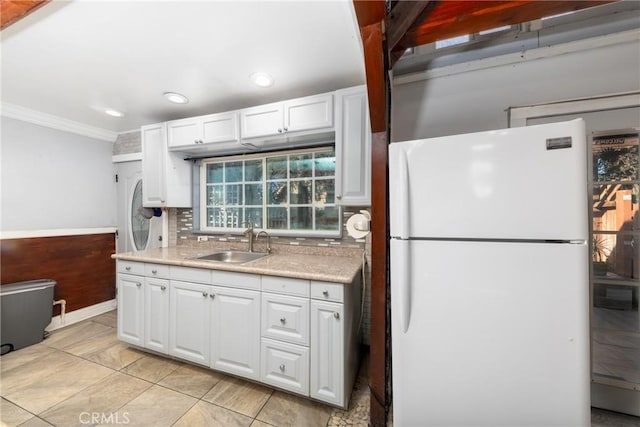 kitchen featuring white fridge, tasteful backsplash, ornamental molding, white cabinets, and sink