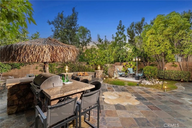 view of patio with an outdoor kitchen, a fire pit, and area for grilling