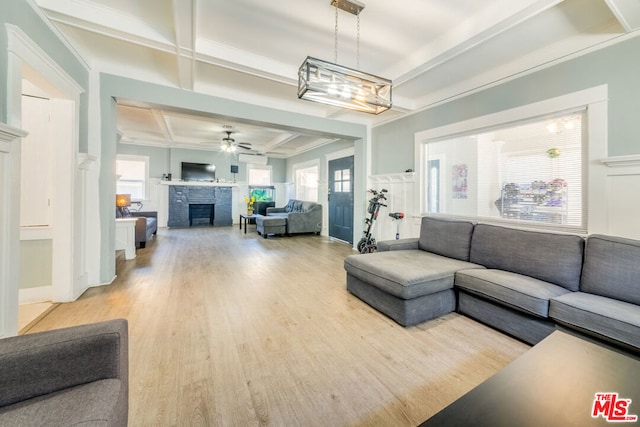 living room featuring ceiling fan with notable chandelier, a healthy amount of sunlight, a fireplace, and light hardwood / wood-style floors