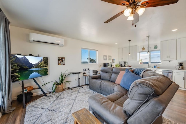 living room with ceiling fan, light hardwood / wood-style floors, and a wall mounted air conditioner