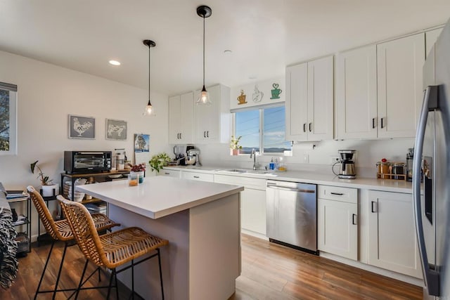 kitchen featuring stainless steel appliances, a kitchen breakfast bar, a kitchen island, white cabinets, and sink