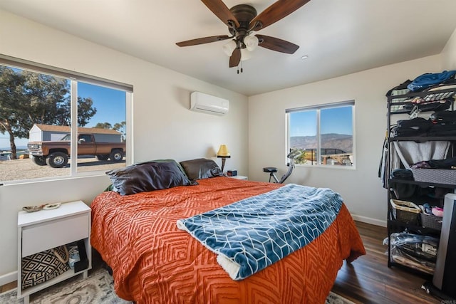 bedroom with ceiling fan, dark hardwood / wood-style flooring, and a wall mounted AC