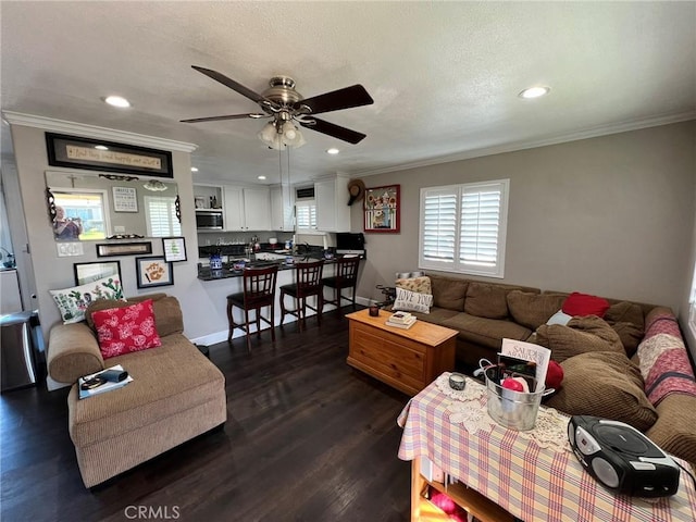 living room with dark wood-type flooring, ceiling fan, and crown molding