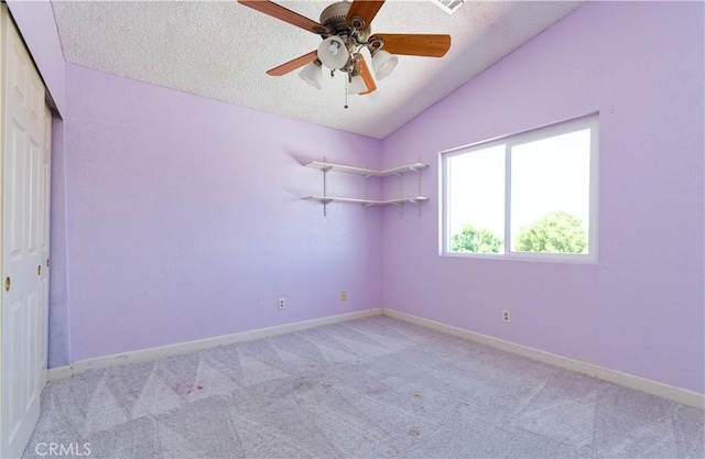 unfurnished room featuring lofted ceiling, ceiling fan, light carpet, and a textured ceiling