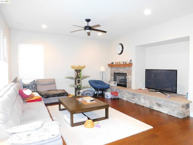 living room with ceiling fan, a stone fireplace, and hardwood / wood-style floors