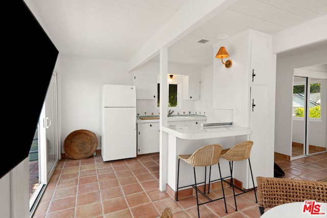 kitchen featuring white cabinets, kitchen peninsula, decorative backsplash, and white fridge