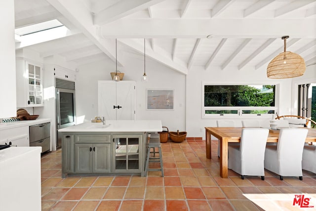 kitchen with white cabinetry, appliances with stainless steel finishes, decorative light fixtures, vaulted ceiling with skylight, and a center island