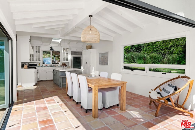 dining space with tile patterned floors, lofted ceiling with beams, and a healthy amount of sunlight