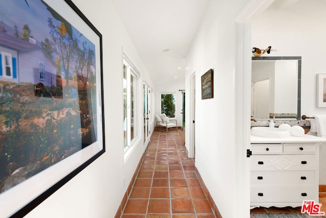 corridor featuring vaulted ceiling, dark tile patterned flooring, and sink