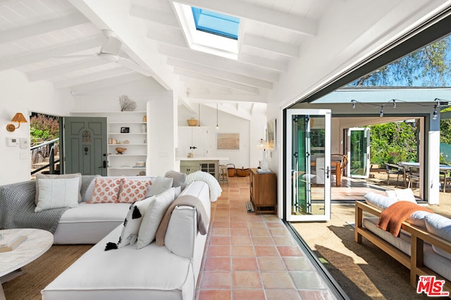 tiled living room with ceiling fan and lofted ceiling with skylight