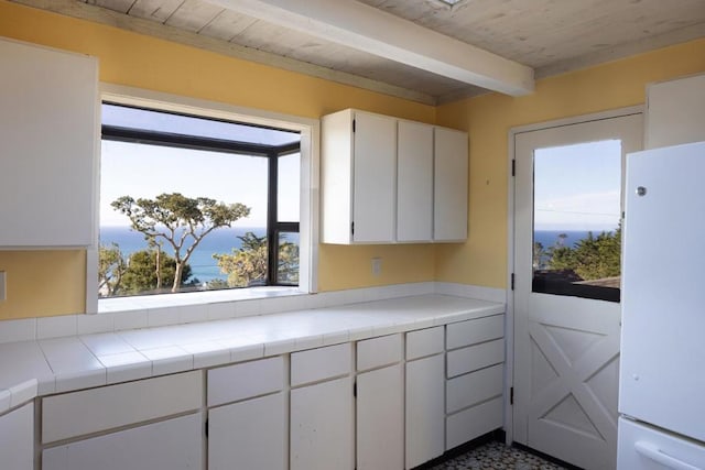 kitchen with white cabinetry, white refrigerator, and tile counters