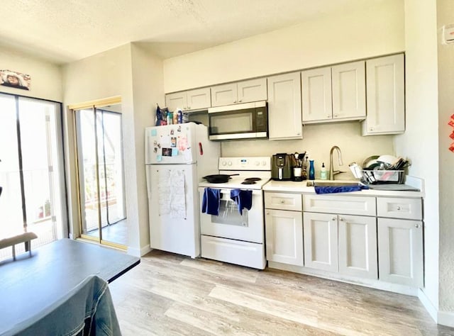 kitchen featuring a textured ceiling, light hardwood / wood-style floors, white appliances, and sink