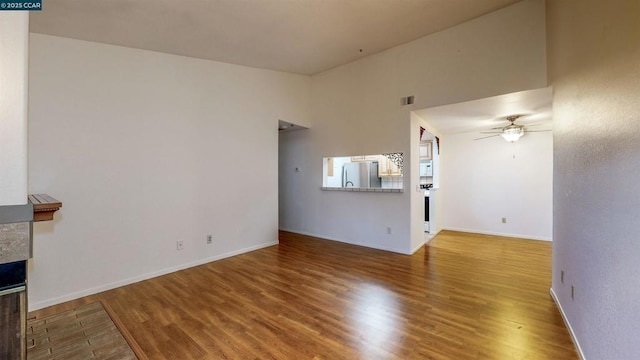 unfurnished living room featuring hardwood / wood-style flooring, ceiling fan, and a fireplace