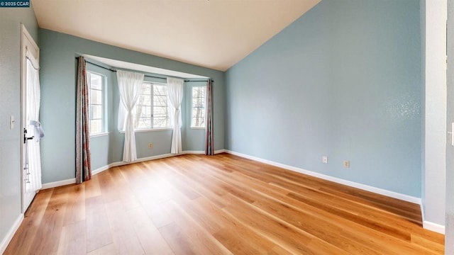 spare room with lofted ceiling and light hardwood / wood-style flooring