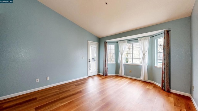 empty room with vaulted ceiling and light hardwood / wood-style floors