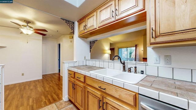 kitchen featuring ceiling fan, tile countertops, dishwasher, and sink