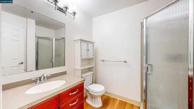 bathroom with a shower with shower door, vanity, toilet, and hardwood / wood-style flooring