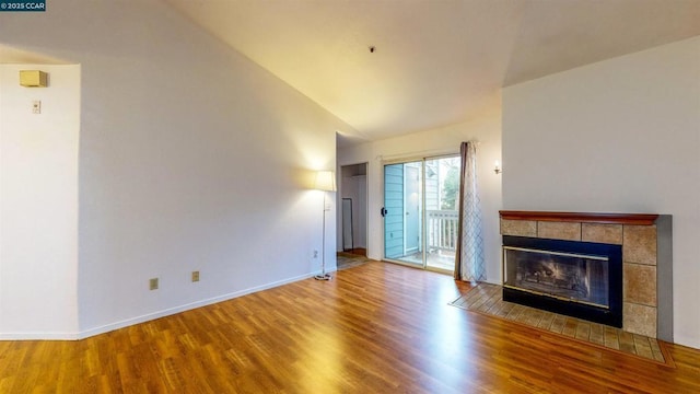 unfurnished living room with light hardwood / wood-style floors, lofted ceiling, and a tiled fireplace