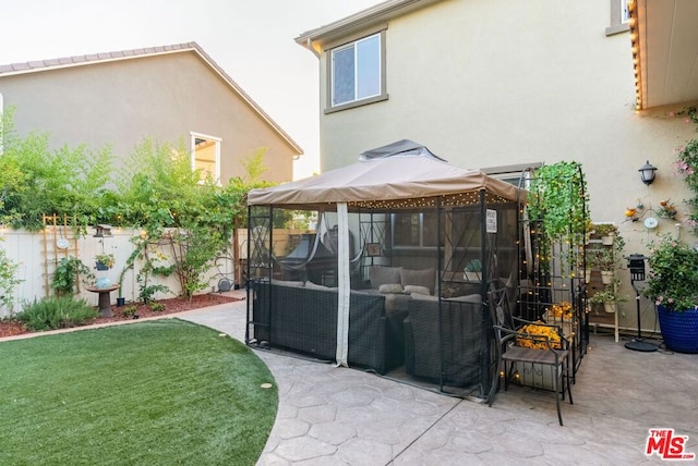 rear view of property with a gazebo, a lawn, and a patio