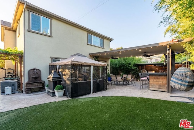 back of property with ceiling fan, central air condition unit, a bar, and a patio