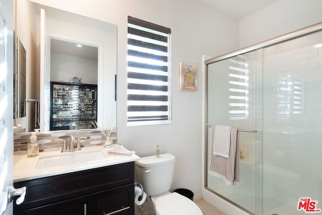 bathroom with a shower with door, toilet, vanity, and tasteful backsplash