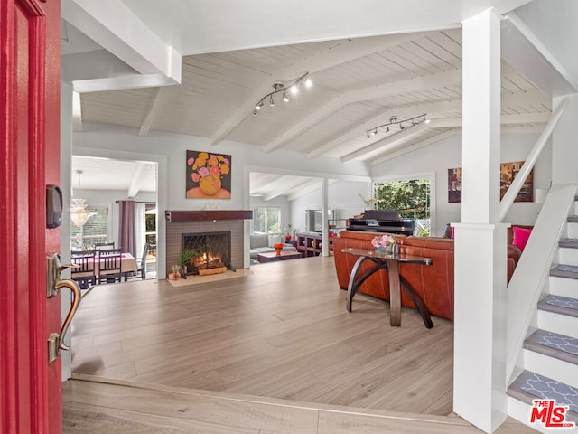 office featuring a brick fireplace, track lighting, lofted ceiling with beams, and light wood-type flooring