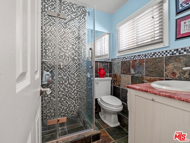 bathroom featuring vanity, a shower with shower door, tile walls, and toilet