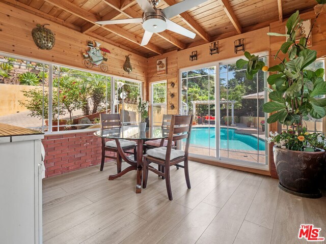 unfurnished sunroom featuring a skylight, wooden ceiling, beamed ceiling, and ceiling fan