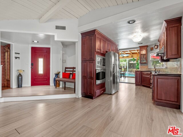 kitchen with appliances with stainless steel finishes, wood ceiling, light wood-type flooring, backsplash, and lofted ceiling with beams