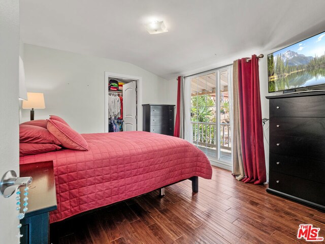 bedroom with wood-type flooring, vaulted ceiling, access to exterior, a walk in closet, and a closet