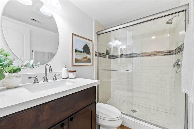 bathroom featuring vanity, toilet, and a shower with door