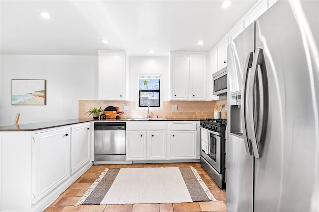 kitchen featuring stainless steel appliances, decorative backsplash, white cabinetry, and sink