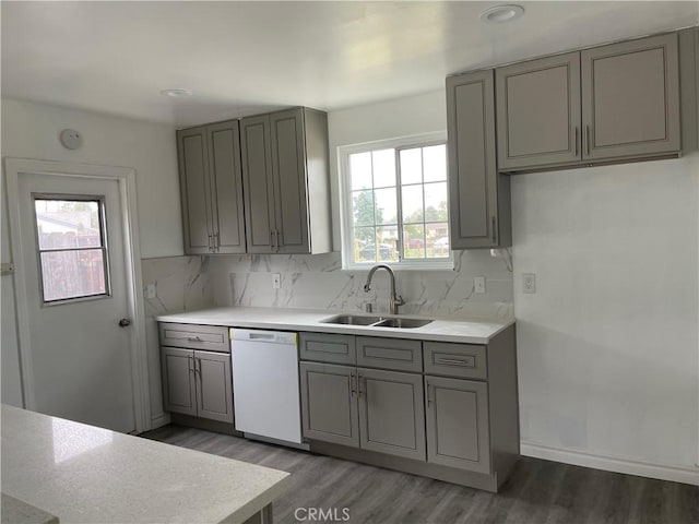 kitchen with tasteful backsplash, dark hardwood / wood-style floors, gray cabinets, sink, and white dishwasher