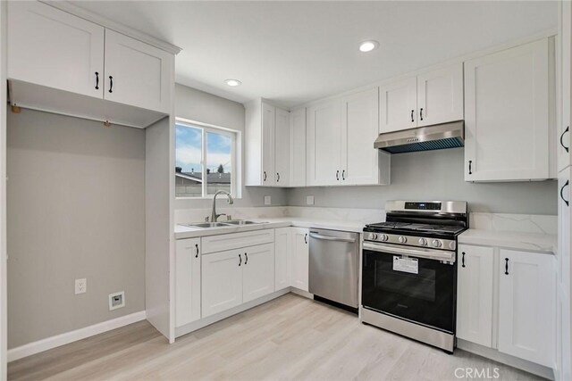 kitchen with white cabinets, appliances with stainless steel finishes, sink, and light hardwood / wood-style floors