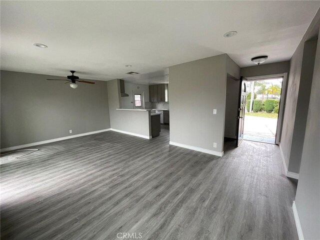 unfurnished living room with ceiling fan and dark wood-type flooring