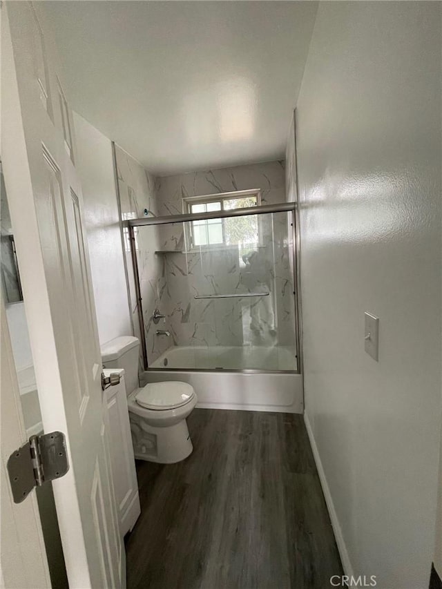 bathroom with toilet, bath / shower combo with glass door, and hardwood / wood-style floors