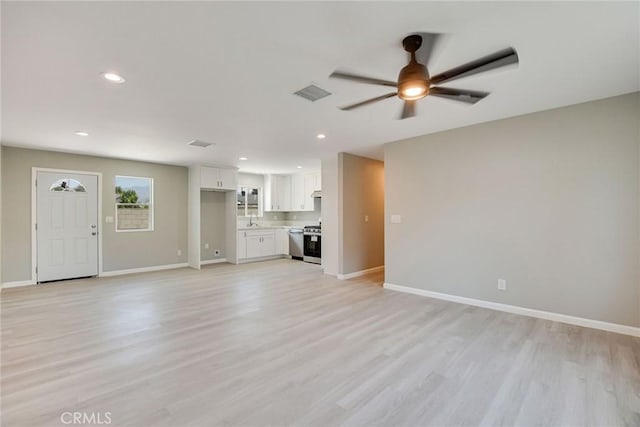 unfurnished living room featuring ceiling fan, light wood-type flooring, and sink