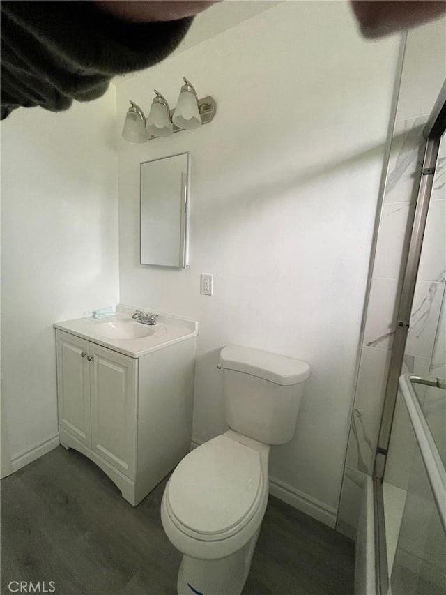 bathroom featuring toilet, walk in shower, wood-type flooring, and vanity