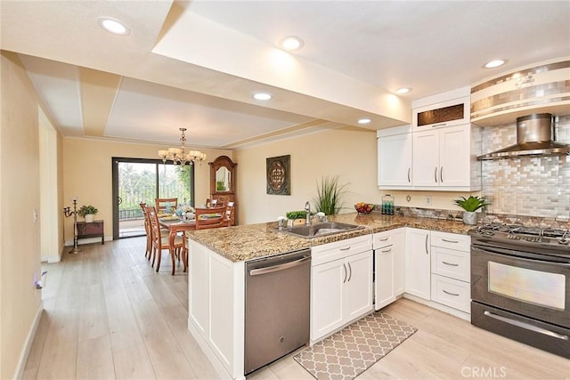 kitchen with dishwasher, wall chimney range hood, white cabinets, and gas stove