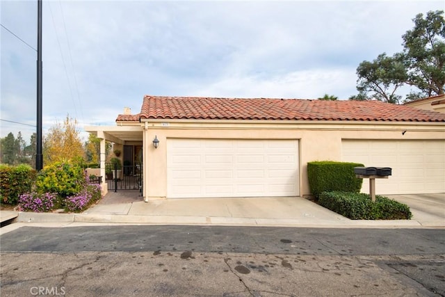 mediterranean / spanish home featuring a garage, a tiled roof, and stucco siding