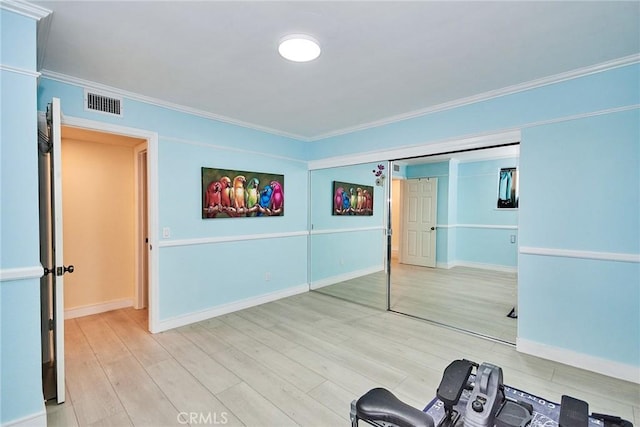 interior space featuring baseboards, wood finished floors, visible vents, and crown molding