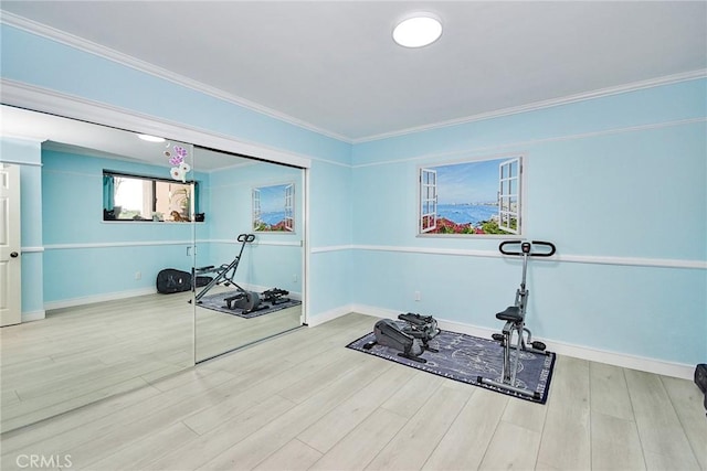 workout area featuring baseboards, light wood finished floors, and crown molding