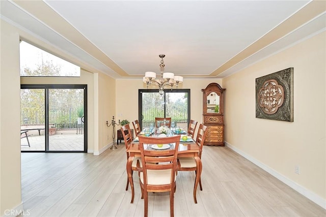 dining space with crown molding, light wood-type flooring, and an inviting chandelier