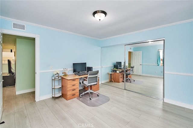 office area featuring light wood finished floors, baseboards, visible vents, and ornamental molding