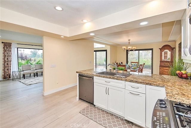 kitchen with a tray ceiling, white cabinetry, a sink, and stainless steel dishwasher