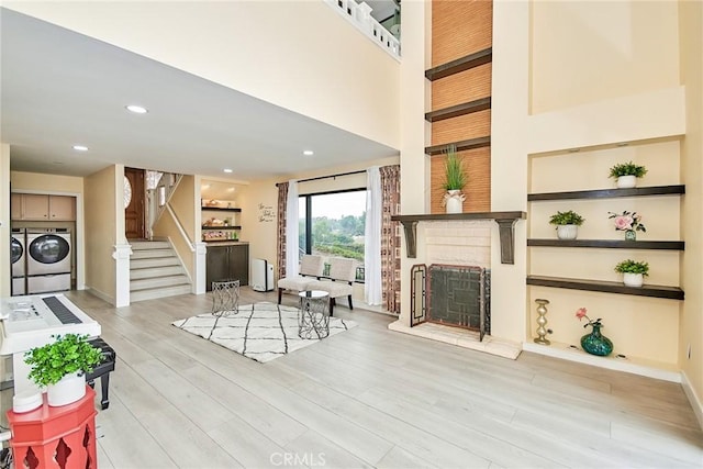 living area featuring a fireplace, recessed lighting, light wood-style floors, independent washer and dryer, and stairs