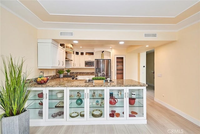 kitchen with stainless steel appliances, visible vents, glass insert cabinets, white cabinetry, and a peninsula