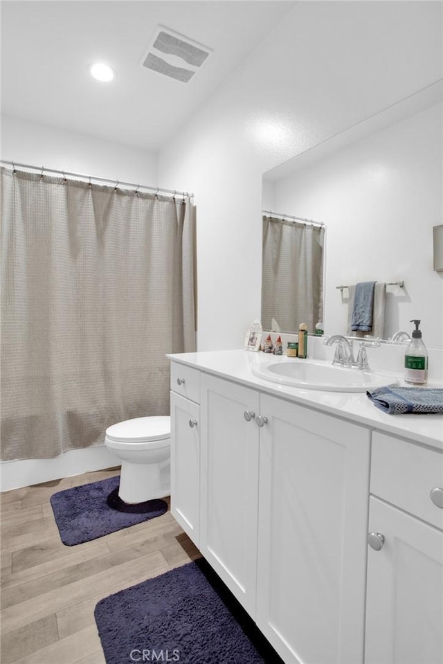 bathroom with toilet, vanity, and hardwood / wood-style flooring