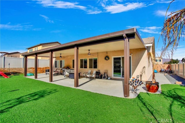 rear view of house with ceiling fan, a patio area, and a yard