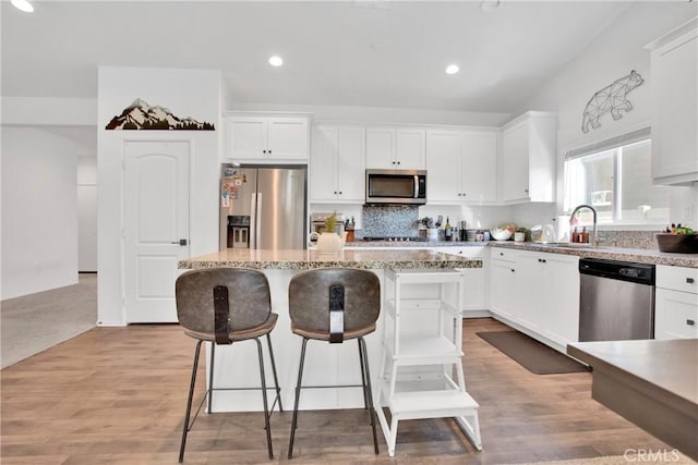 kitchen with appliances with stainless steel finishes, white cabinetry, and a kitchen island